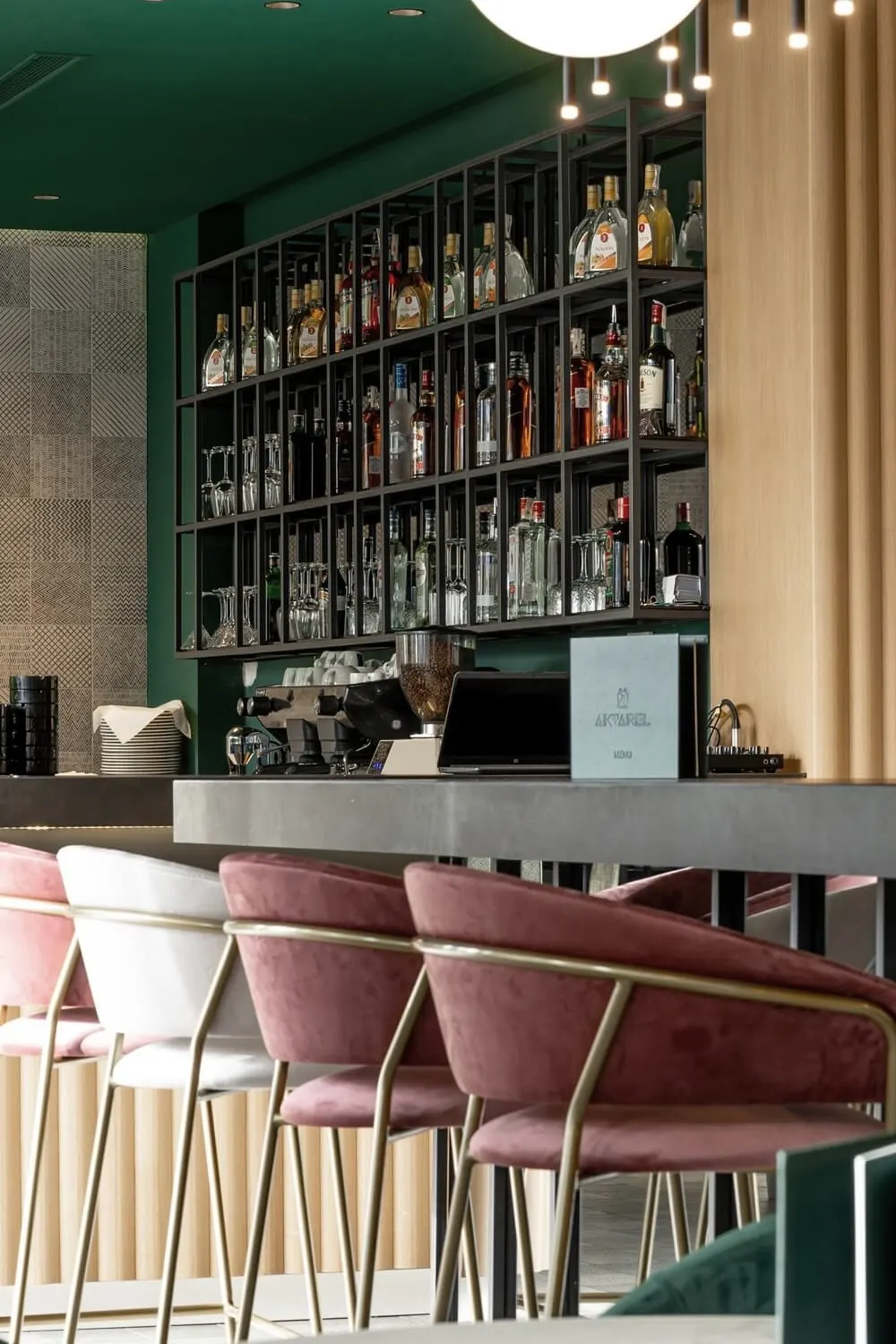 Bar restorana Akvarel sa policama za pića i roze baršunastim barskim stolicama