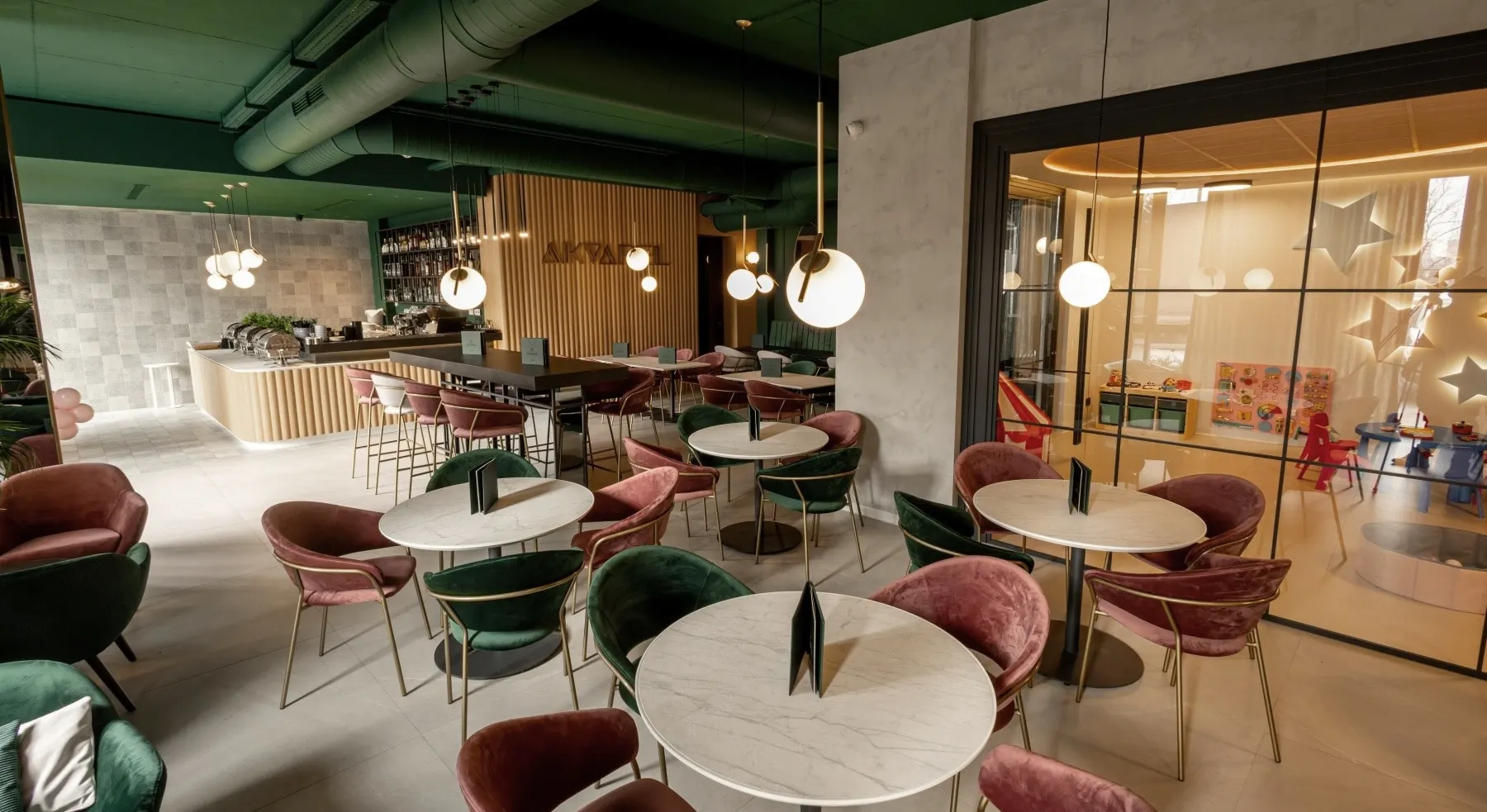 Sala restorana Akvarel sa mermernim stolovima i zastakljenom igraonicom u pozadini