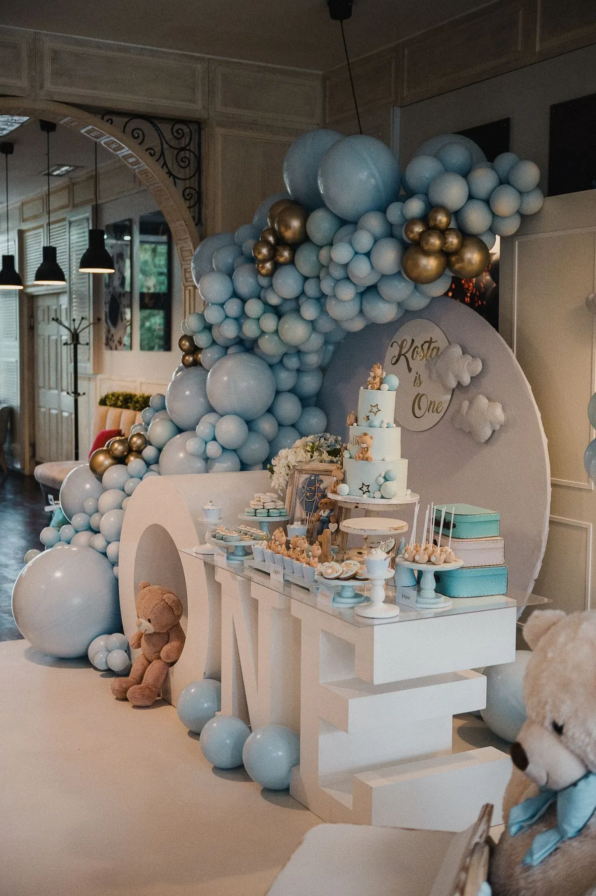 Dekoracija sa plavim balonima i slatkim stolom za prvi rođendan u restoranu Sweet & Salty